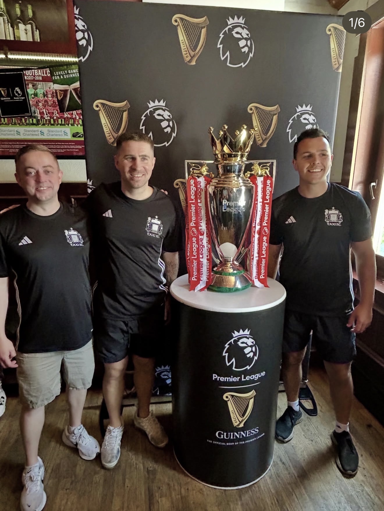 Taxi FC players posing with the Premier League trophy inside the pub